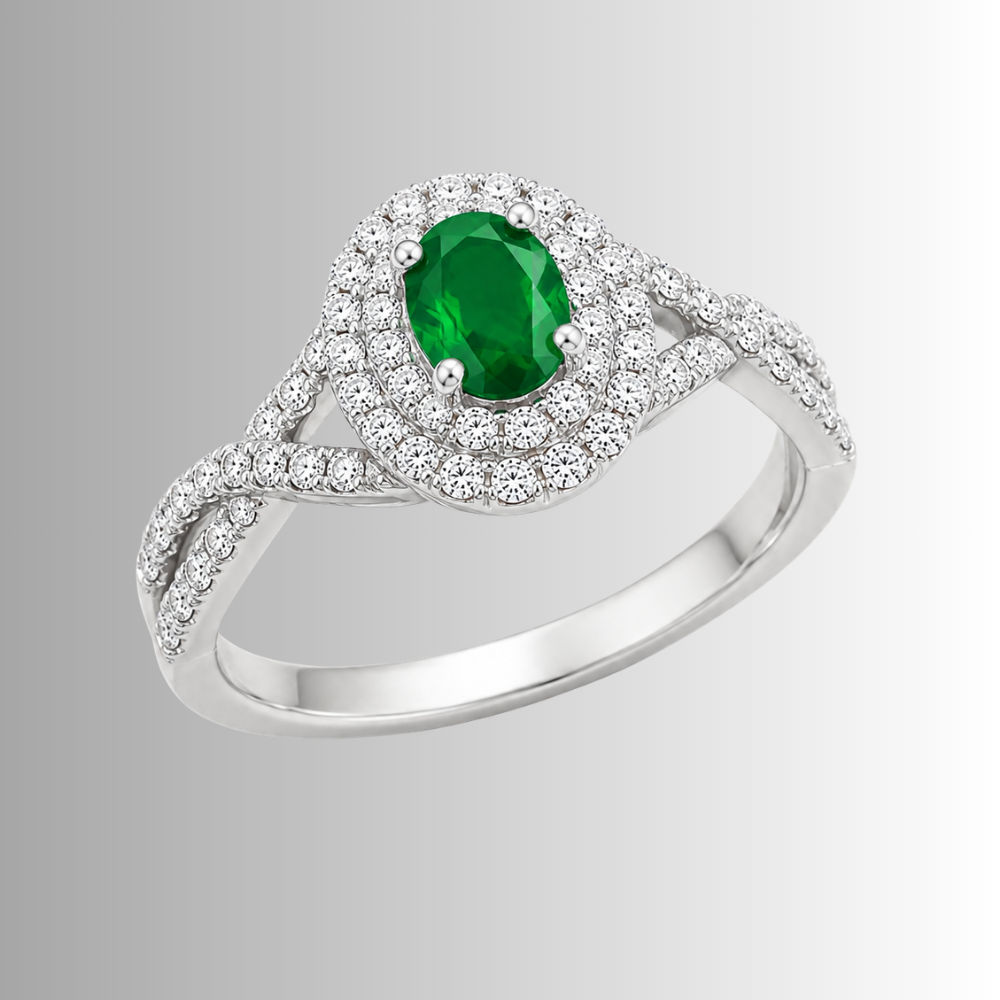 A silver-toned halo ring featuring a round-cut green emerald center stone and pavé-set round diamonds, shown on a light gray gradient background.